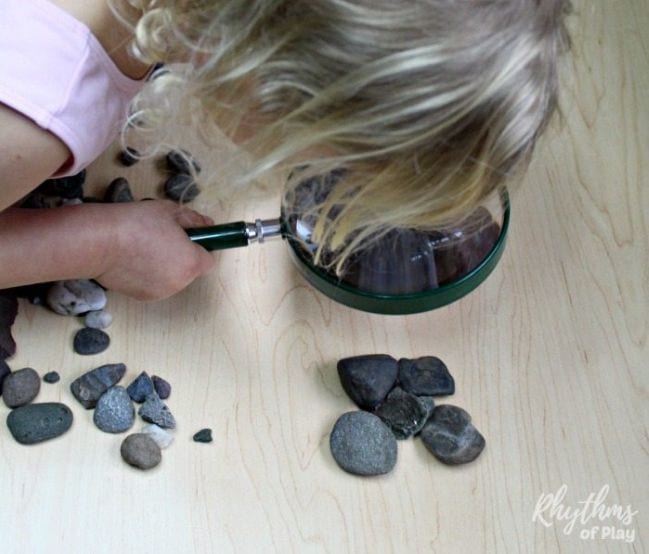 Classifying Rocks Child peering at a pile of rocks through a magnifying glass