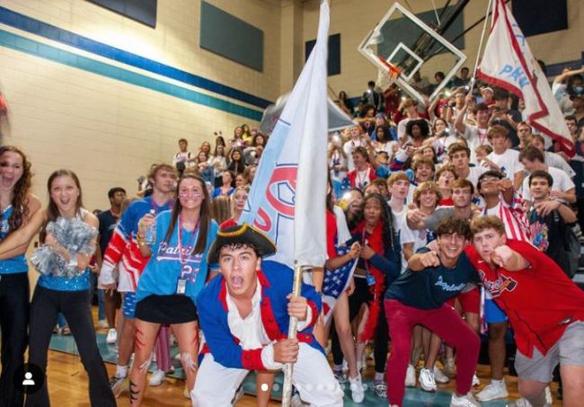 Spirit Week Ideas: Competitions Students at a school pep rally wearing school colors and cheering